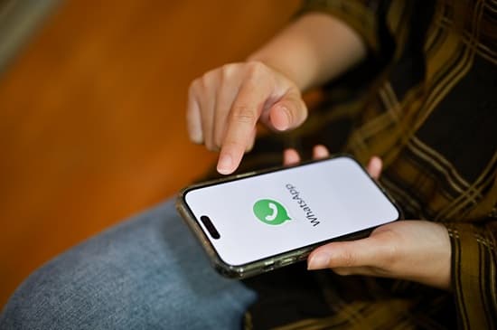 Pessoa usando celular com ícone do WhatsApp e símbolo da Justiça Eleitoral