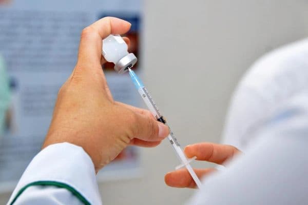 Profissional de saúde aplicando vacina contra gripe em posto de saúde público