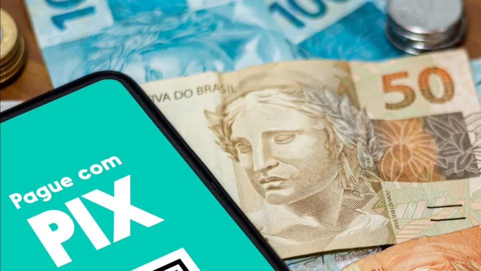 Mão segurando celular com tela de transferência Pix aberta