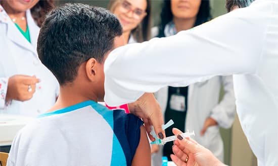 Profissional de saúde aplicando vacina contra influenza em posto de saúde