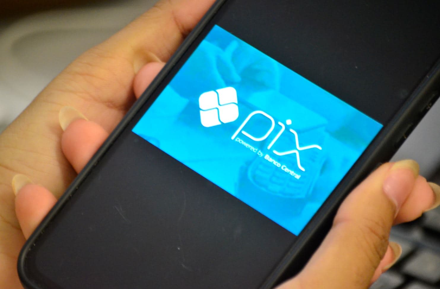 Pessoa realizando pagamento via Pix por aproximação em maquininha com smartphone Android
