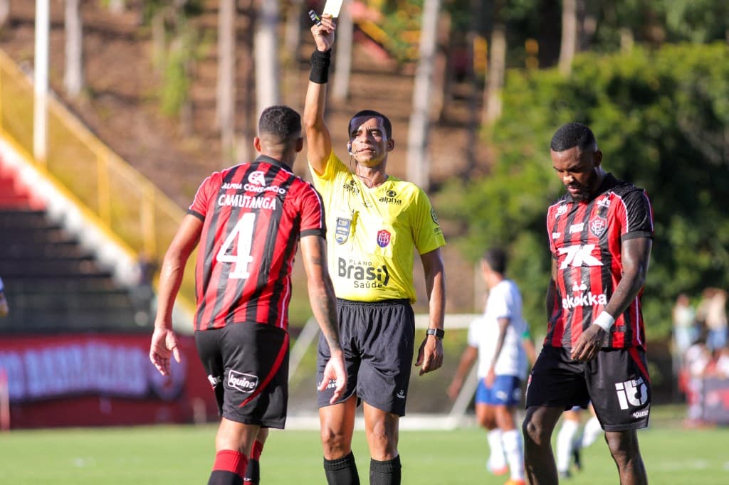 Árbitro exibindo cartão amarelo em partida de futebol