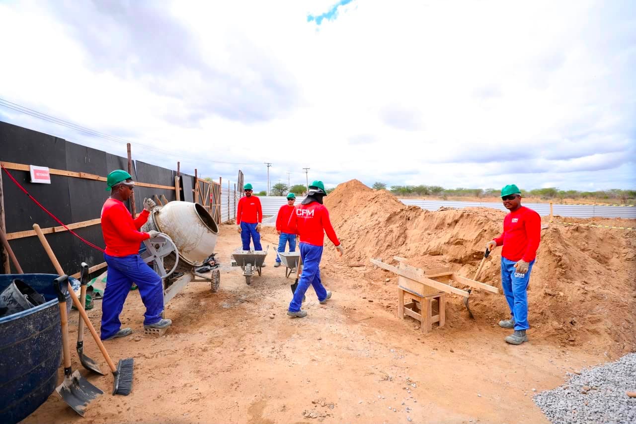 Vista de canteiro de obras de pavimentação no Sertão de Pernambuco com máquinas e operários trabalhando em rodovia