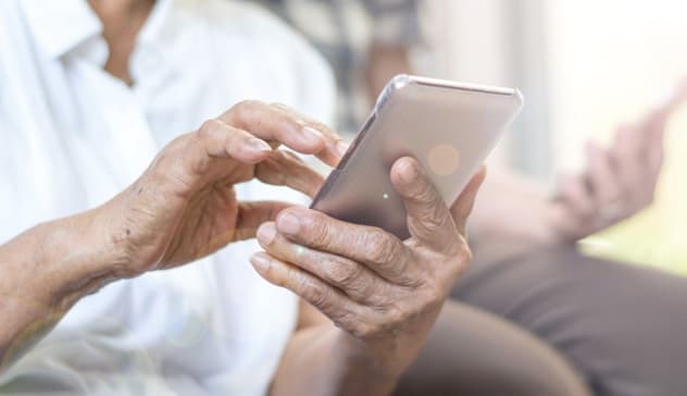 Pessoa usando celular com ícone de cadeado e alerta de segurança digital sobreposto, representando tentativas de fraude de identidade