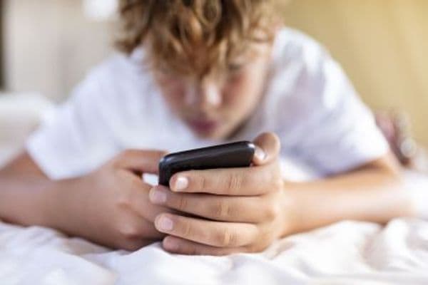 Criança sentada no sofá usando tablet durante as férias escolares