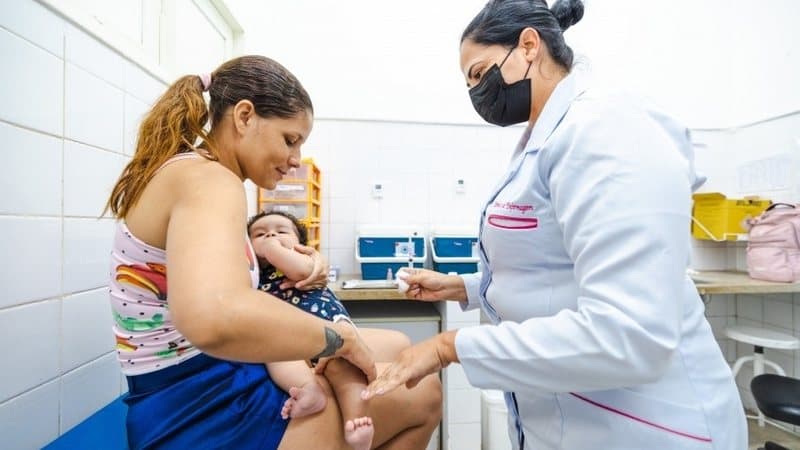 Criança recebendo vacina Pneumo 20 em unidade básica de saúde