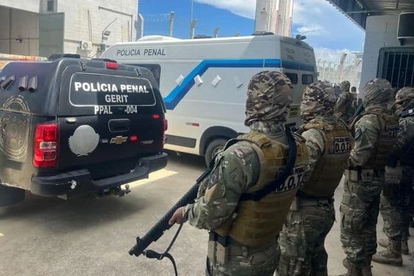 Entrada de unidade prisional com grades e corredor interno, representando o sistema carcerário brasileiro