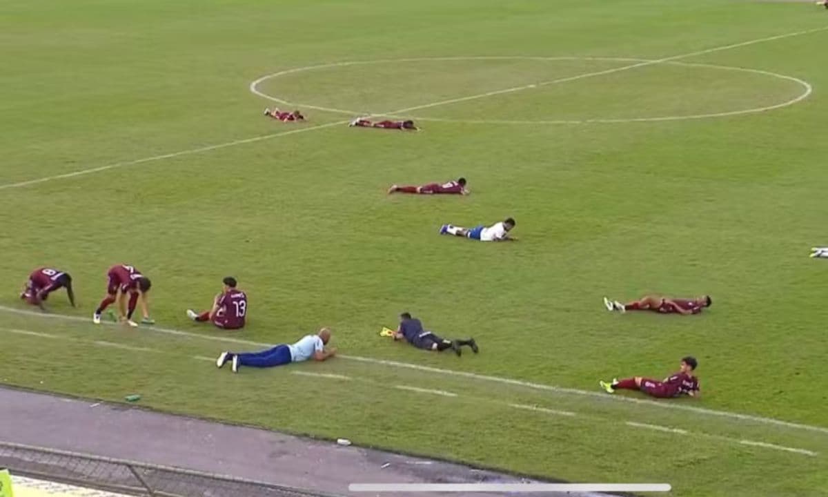 Jogadores deitados no gramado do Estádio Joia da Princesa durante invasão de abelhas na final do Baianão sub-20