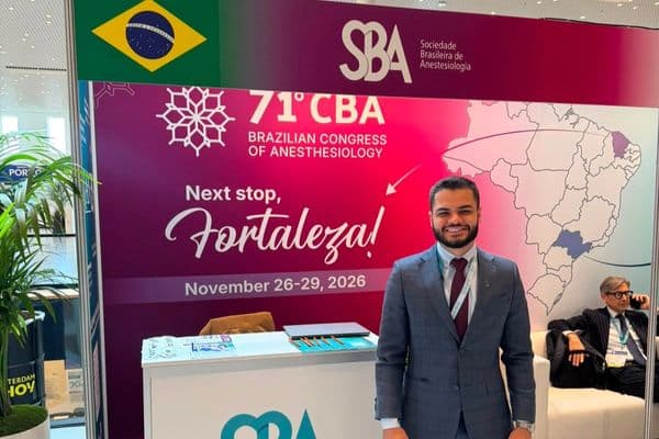 Médico anestesiologista segurando diploma em cerimônia de certificação internacional