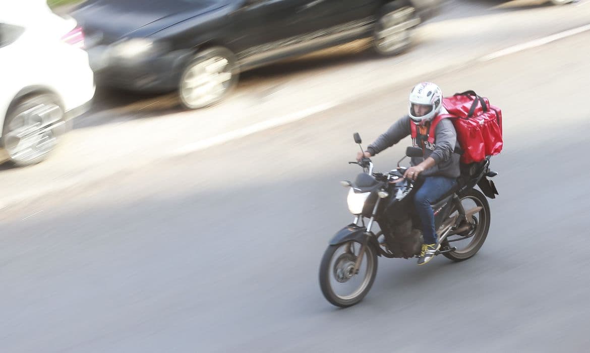 Entregador de aplicativo em moto nas ruas do Brasil