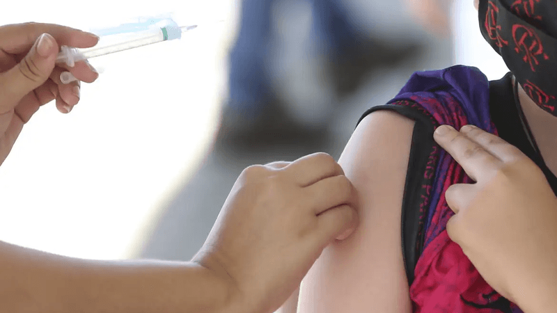Profissional de saúde aplicando vacina contra HPV em adolescente em unidade básica de saúde