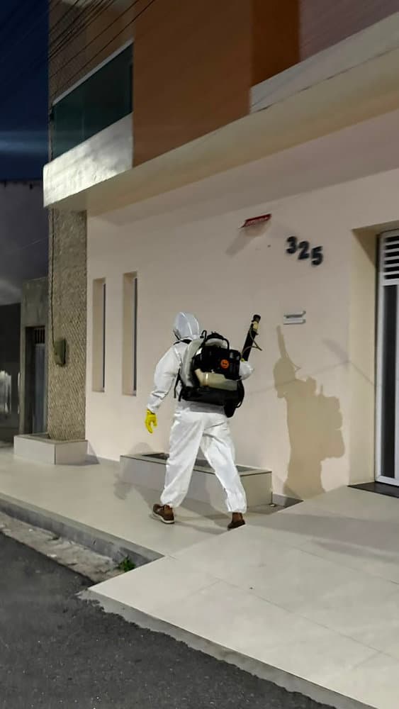 Agente de endemias com bomba costal motorizada em ação de combate ao Aedes aegypti em bairro urbano