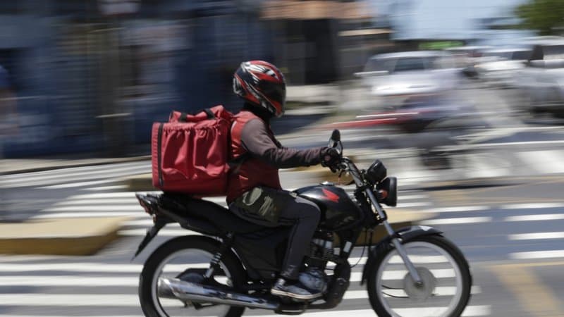 Entregador de aplicativo em motocicleta nas ruas do Brasil