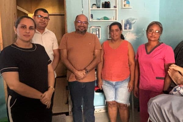 Profissional de saúde realizando atendimento domiciliar a paciente acamado