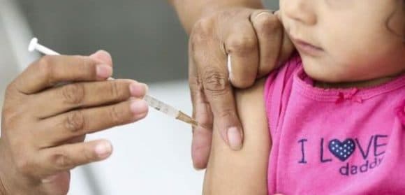Profissional de saúde aplicando vacina contra gripe em posto de saúde na Bahia