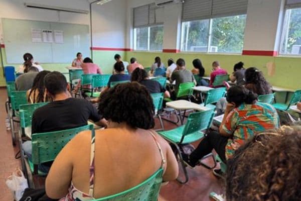 Candidatos em sala de prova com fiscais de concurso público supervisionando