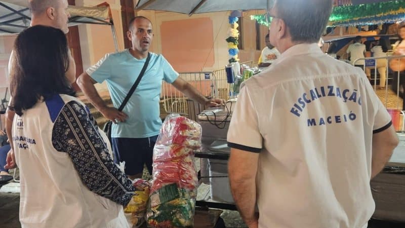 Fiscal da Vigilância Sanitária inspecionando barraca de alimentos em evento junino de Maceió