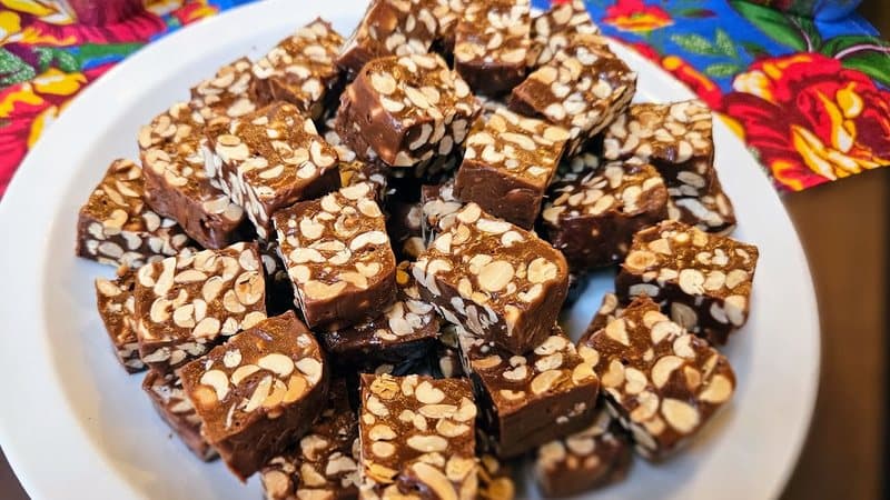 Pé-de-moleque cremoso com amendoim e chocolate, cortado em pedaços sobre tábua rústica