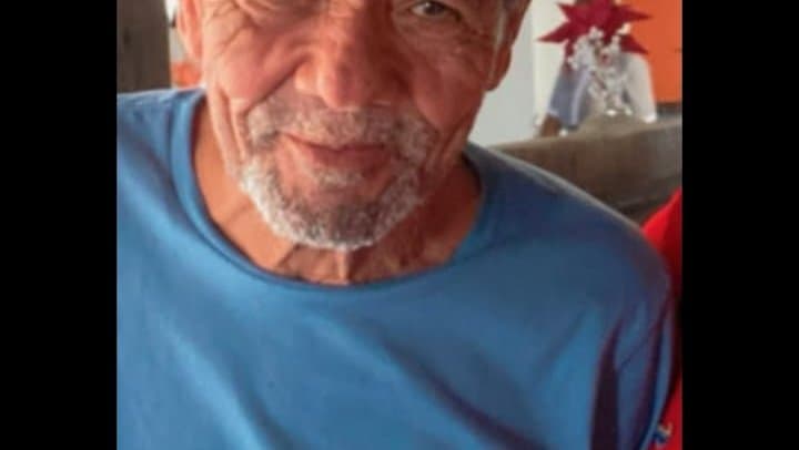Homem idoso caminhando sozinho em rua de centro urbano