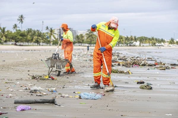 Garis com uniformes de trabalho em frente a caminhão de coleta de lixo durante paralisação nacional