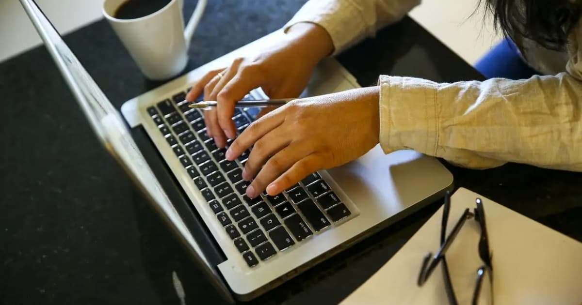 Mulher utilizando celular e computador para acessar formação digital