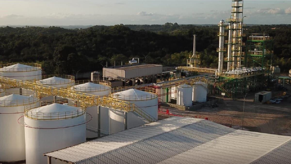 Refinaria de petróleo com torres de destilação e estrutura industrial ao entardecer