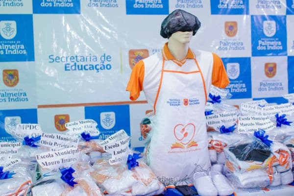 Merendeiros com equipamentos de proteção individual em cozinha escolar