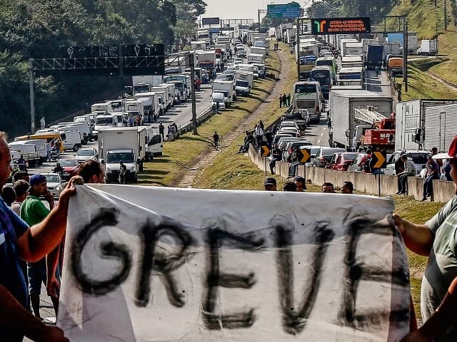 Caminhões parados em fila próximos a porto durante paralisação da categoria