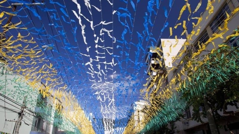 Caminhão de coleta de lixo em rua decorada com bandeirinhas do Brasil para a Copa do Mundo