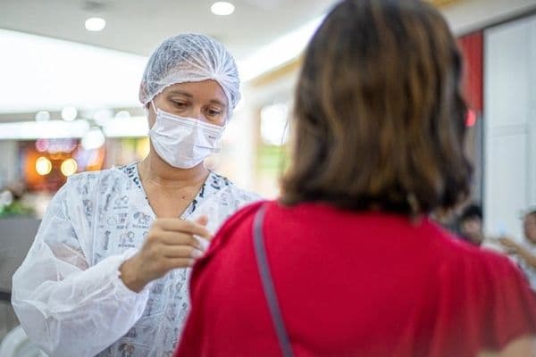 Ponto de vacinação em funcionamento em espaço público, com profissional de saúde atendendo população