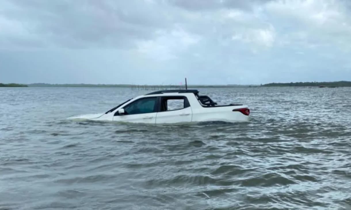 Picape Fiat Toro atolada na areia da praia com água do mar ao redor