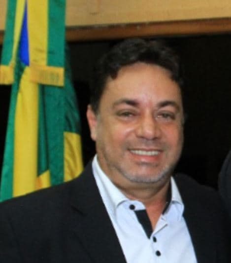 Tela de computador exibindo símbolo de inteligência artificial com elementos de urna eletrônica e bandeira do Brasil ao fundo