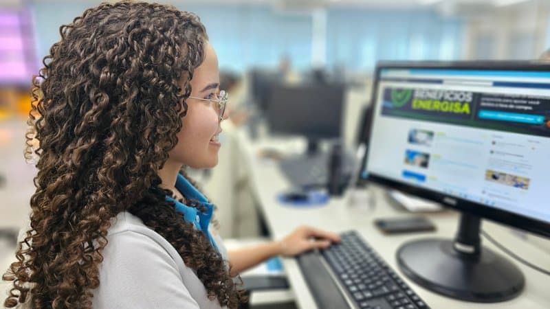 Jovem trabalhando em frente a computador com planilhas e gráficos de dados