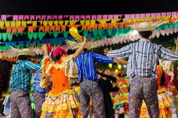 Fogueira de São João com decoração junina ao fundo, representando o feriado de 24 de junho