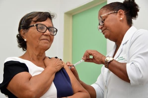 Profissional de saúde aplicando vacina contra influenza em posto de vacinação