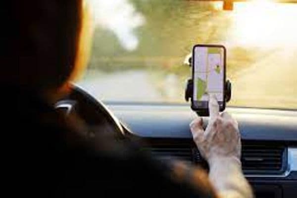Motorista de aplicativo com celular exibindo mapa de navegação dentro do veículo