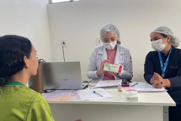 Profissional de saúde inserindo implante contraceptivo subdérmico no braço de paciente em unidade básica de saúde