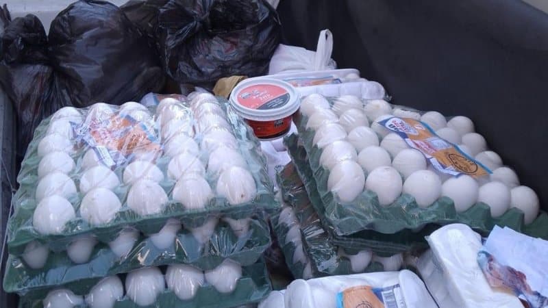 Fiscal da Vigilância Sanitária inspecionando alimentos em prateleiras de estabelecimento comercial