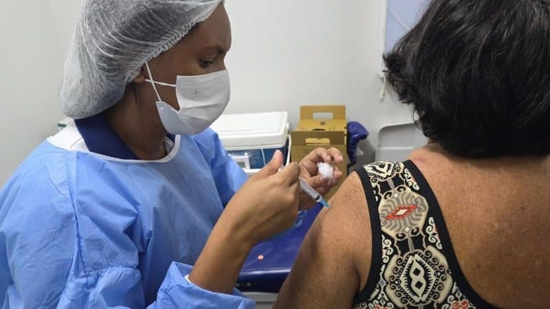 Profissional de saúde aplicando vacina contra gripe em posto de saúde
