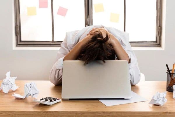 Trabalhador com expressão de cansaço em frente a computador, representando sintomas do burnout silencioso