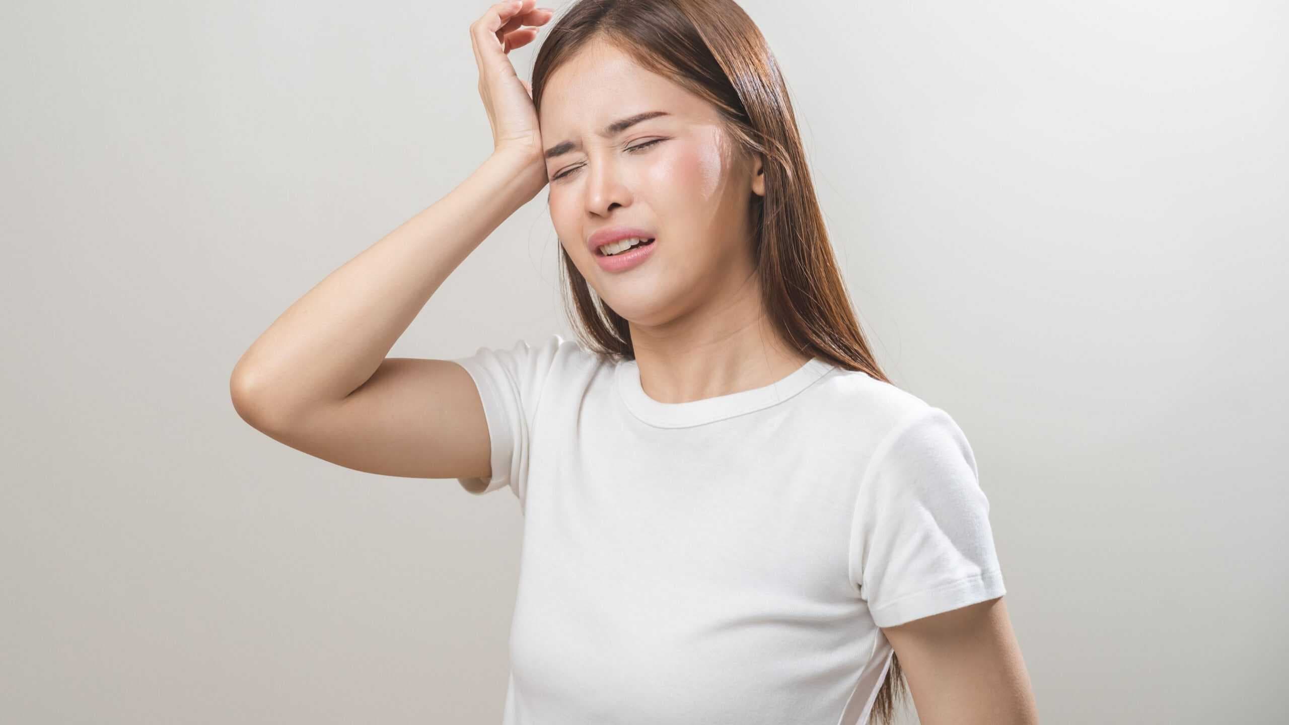 Jovem asiática com dor de cabeça ou enxaqueca, sofrendo de vertigem / Crédito: Kmpzzz (Shutterstock)