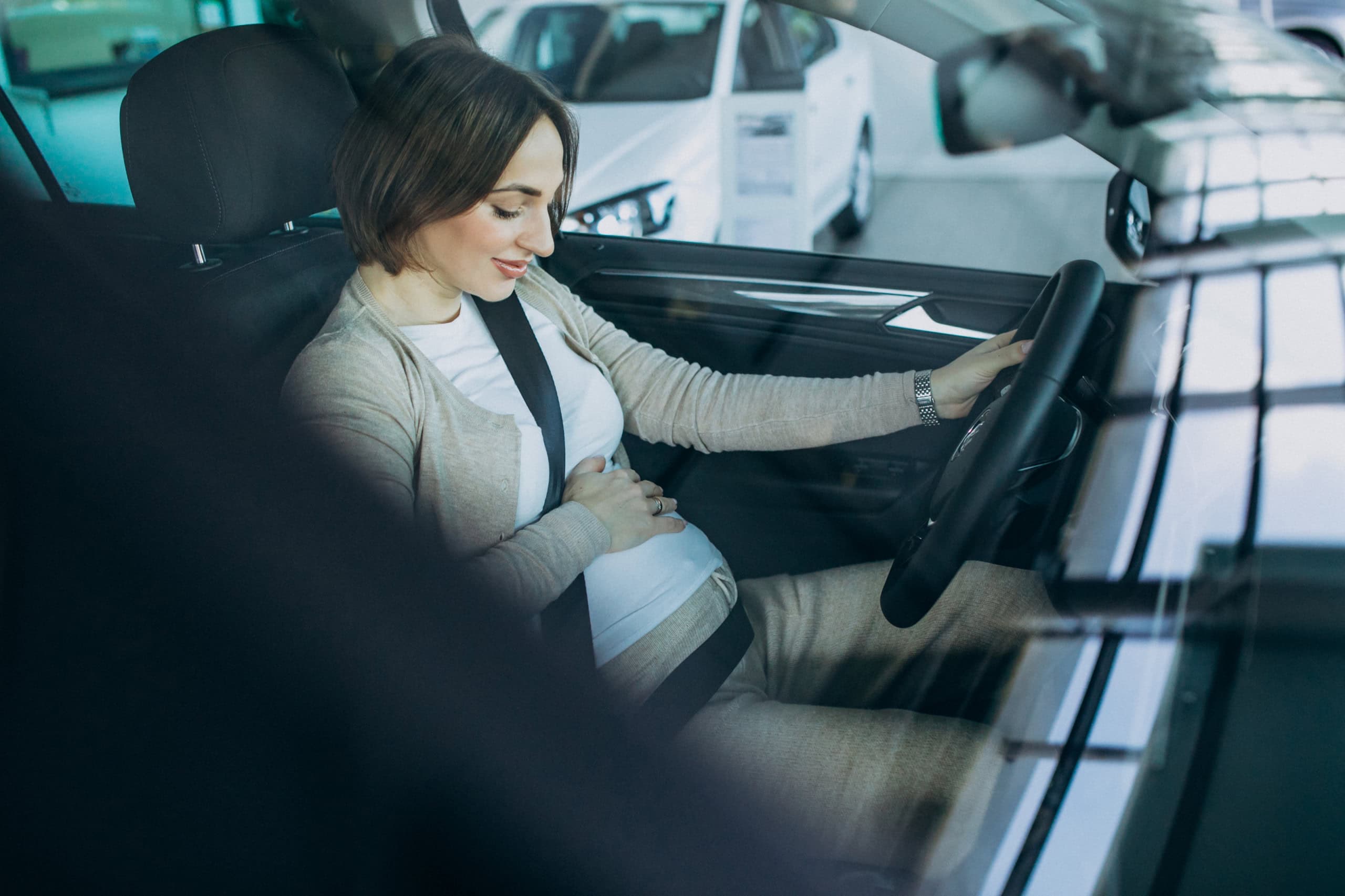 Gestante testando um carro numa loja de automóveis (Imagem: senivpetro/Freepik)
