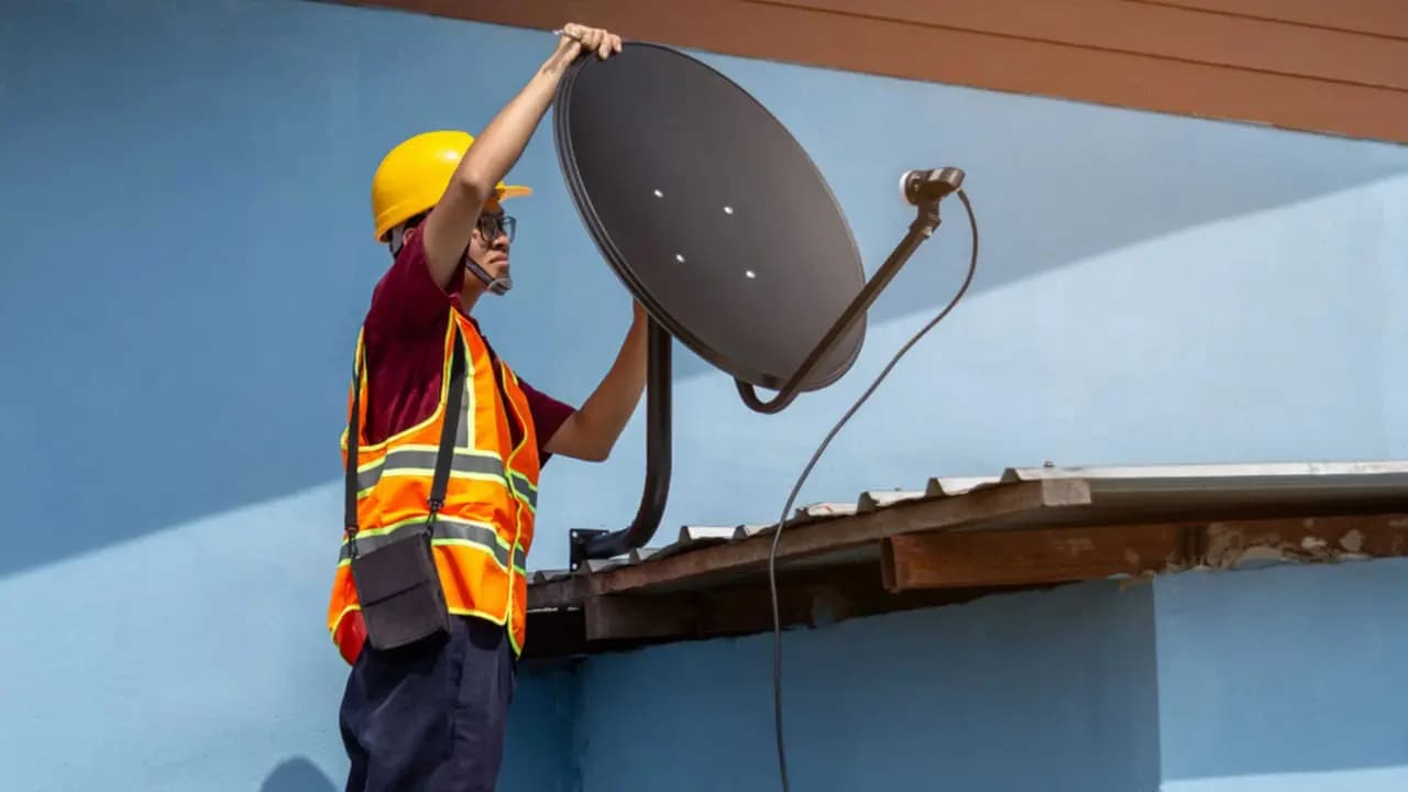Profissional realizando a instalação de uma antena parabólica - Imagem:PitukTV/Shutterstock