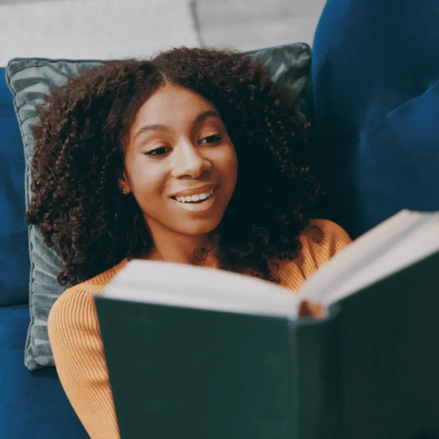 Mulher Lendo Um Livro Enquanto Está Deitado Em Um Sofá (Reprodução: Vidi Studio/Shutterstock)