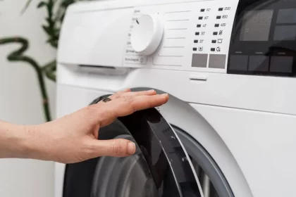 Mulher Abre Ou Fecha A Porta De Máquina De Lavar Automática Com Painel Digital Moderno / Crédito: Brizmaker – Shutterstock (Divulgação)